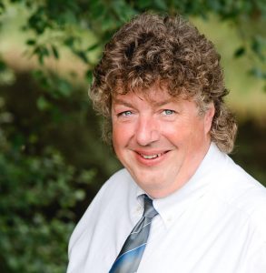 Holger Peters im Jahr 2008 beim Fotoshooting im Grünen für den Immobilien-Shop Holger Peters Uplengen, umgeben von üppigem Laub und strahlendem Sonnenschein in Ostfriesland